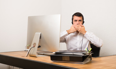 Telemarketer man in a office covering mouth with hands for saying something inappropriate