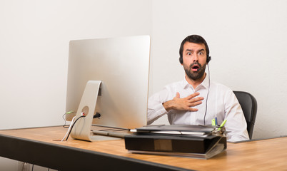 Telemarketer man in a office surprised and shocked while looking right
