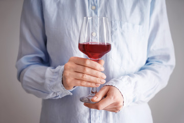 Woman with glass of wine on light background, closeup