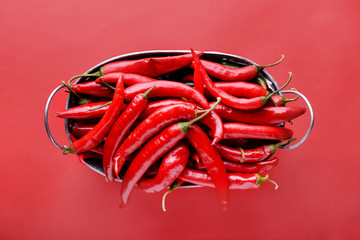 Basket with fresh chili peppers on color background