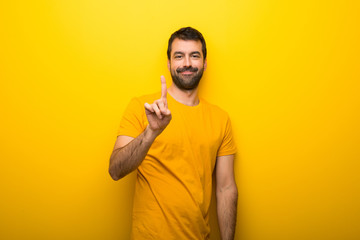 Man on isolated vibrant yellow color showing and lifting a finger