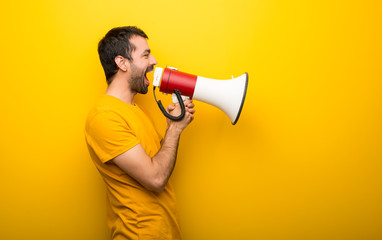 Man on isolated vibrant yellow color shouting through a megaphone to announce something in lateral position