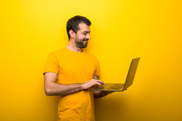 Man on isolated vibrant yellow color with laptop