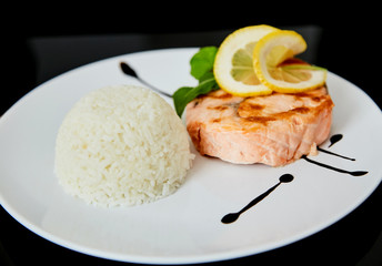 Fish fillet with rice. Dish on black background.