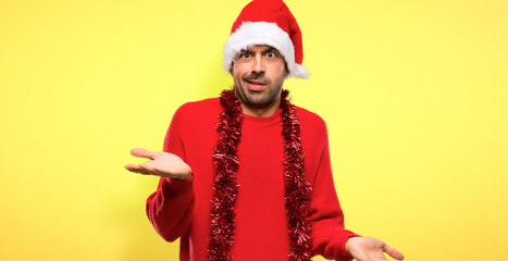 Fototapeta premium Man with red clothes celebrating the Christmas holidays unhappy and frustrated with something because not understand something on yellow background