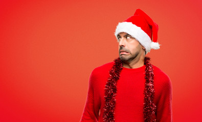 Man with red clothes celebrating the Christmas holidays is a little bit nervous and scared pressing the teeth on red background