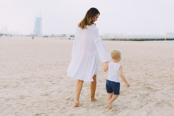Young mother and happy little son at sandy beach in Dubai, UAE