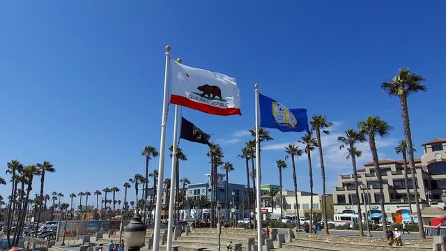 slow motion footage of the California state flag, MIA-POW flag, and the Huntington Beach City flag flying in Huntington Beach California. 4K