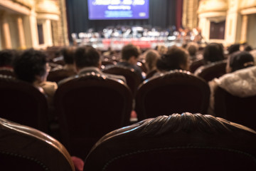 Blurred Audience in a theater, on a concert. Viewers watching the show.