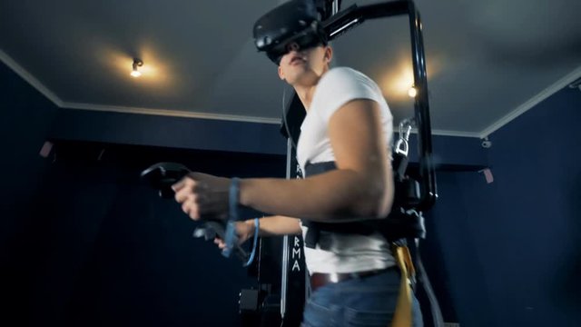 Virtual reality platform and a young man using it in a playing process. Virtual reality gaming concept.