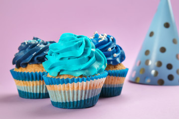 Tasty birthday cupcakes on color background