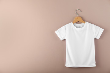 Hanger with blank white t-shirt on color background