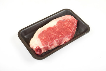 Raw sirloin beef steak in plastic packaging tray.