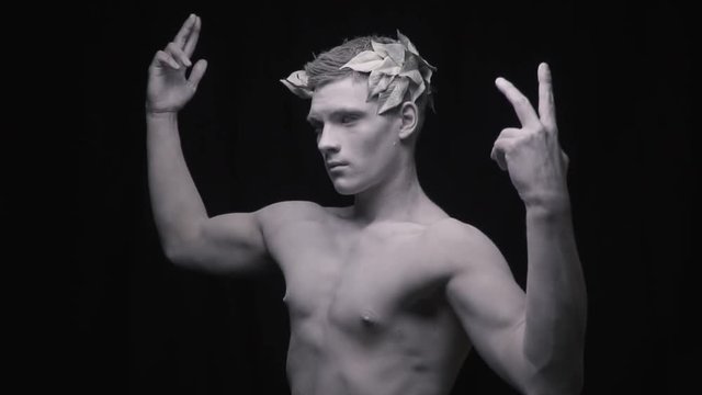Living statue of the fit man spreads his arms and flexes