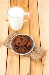 Glass cup of milk and chocolate biscuits on a wooden background