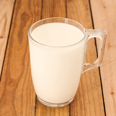 A glass cup of milk on a wooden background. Close up