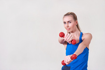 Female athlete doing exercise with dumbbell. Copy space. Concept of health and body care.