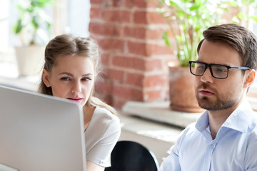 Close up of serious diverse employees look at computer screen, think of business strategy or solve...