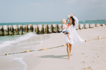 Young mother and happy little son at sandy beach in Dubai, UAE