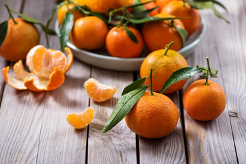 Tangerines, mandarin fresh citrus fruits with leaves on wooden background