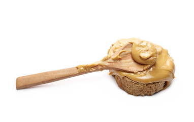Peanut butter spread on slice of bread with wooden spoon isolated on white background