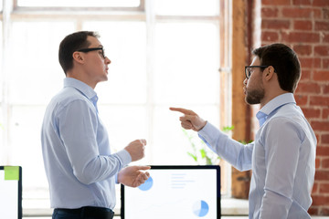 Mad male colleagues have disagreement in office arguing on work issues, furious millennial employee point at coworker blaming for mistake or failure, businessman accuse partner disputing at workplace - obrazy, fototapety, plakaty
