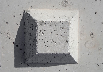 The truncated square pyramid shape on the concrete surface. The surface is  plain, but with many small holes, gray color background