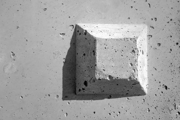 The truncated square pyramid shape on the concrete surface. The surface is  plain, but with many small holes, gray color background