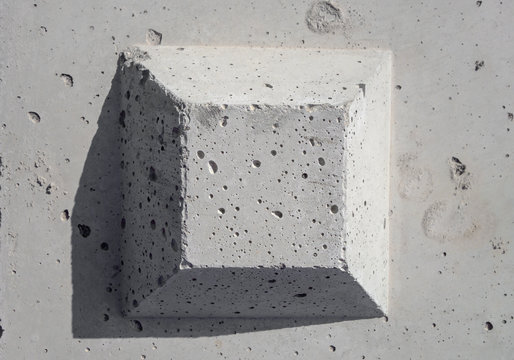 The truncated square pyramid shape on the concrete surface. The surface is  plain, but with many small holes, gray color background