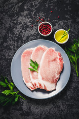Raw fresh meat slices on plate, dark background. Top view, space for text.