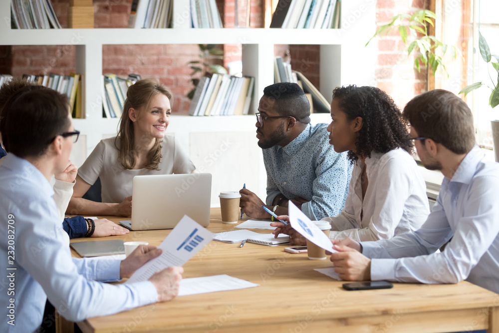 Wall mural Multiracial millennial colleagues brainstorm discussing startup ideas during briefing in boardroom, female CEO hold business meeting with diverse employees, negotiating analyzing report or stats