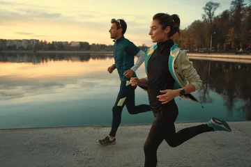 Papier Peint photo Lavable Jogging Jeune homme et femme pour une course sur le lac au lever du soleil