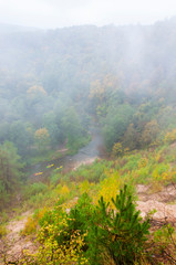 Kayaks on the forest river draped in fog at autumn