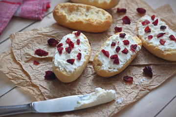 Bruschetta with cottage cheese and dried cranberries over light wooden background