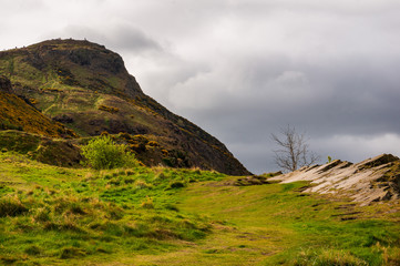 Typical Scottish landscape on a cloudy day with hills covered in green grass. Arthur's Seat hill view from below in Edinburgh, Scotland.