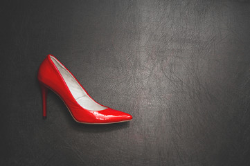 Black and red. Lacquered red shoe on a hairpin on a black background