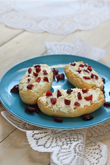 Bruschetta with cottage cheese and dried cranberries over light wooden background