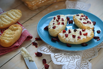 Bruschetta with cottage cheese and dried cranberries over light wooden background