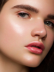 Close-up beauty woman with clean shiny skin and natural cosmetics. Fashion, spa, cosmetology, lip injections, eyeshadow on brown eyes and thick eyebrows, cosmetics, make-up, beautiful
