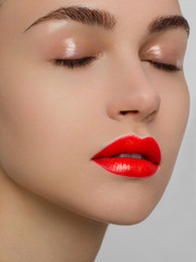 Naklejka premium Zbliżenie piękno kobieta z czystą błyszczącą skórą i jaskrawym makeup. Moda, spa, kosmetologia, zastrzyki w czerwone usta, cienie na brązowych oczach i grube brwi, kosmetyki, makijaż, piękne