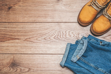  Jeans and yellow boots on a wooden background. Top view