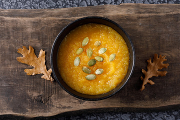 Healthy pumpkin soup on rustic dark wooden board. Delicious vegetarian food.