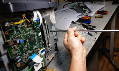 technician repairs photocopier with screwdriver