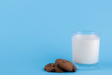 Cookies with chocolate and milk in a glass on a blue bright background. place for text. bake. yummy