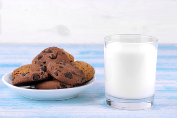 Cookies with chocolate on a plate and milk in a glass on a blue wooden background. Baking. yummy