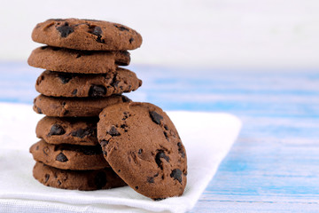 Cookies with chocolate folded in a pile on a white napkin on a blue wooden table. bake. yummy.