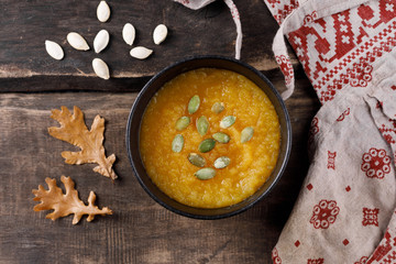 Autumn still life with pumpkin soup in a rustic style. A bowl of soup and an apron on a wooden background.