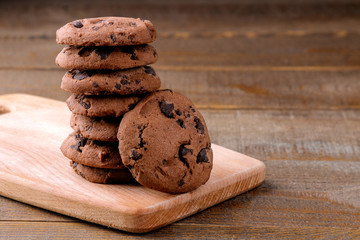Tasty cookies with chocolate on the board on a brown wooden table
