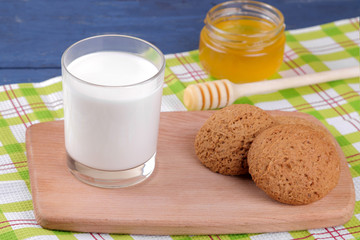 Oatmeal cookies with milk and honey on a board on a blue wooden table