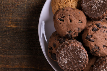 different tasty cookies on a plate on a brown wooden table. top view close up